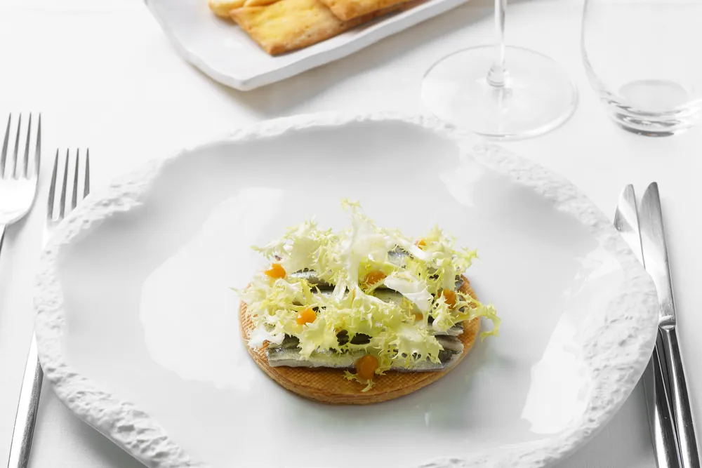 Un tavolo apparecchiato in sala, con la tartelletta di verdure e i calici